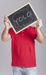 Motivational concept with man holding a board with You Only Live Once (YOLO) message