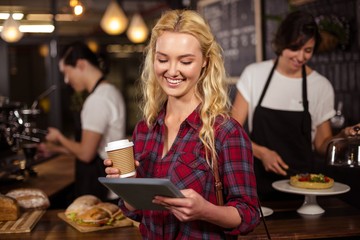 Smiling blonde customer in front of the counter using tablet