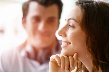 Young pretty woman smiling with man on background