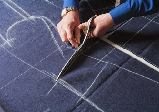 Tailor Cutting Fabric with Scissors.