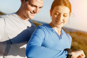 Runner woman with heart rate monitor running on beach
