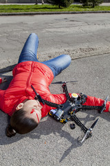 Obraz premium Pretty woman attacked by drone quadrocopter with bleeding head injuries, lying on sidewalk in the city, space for text