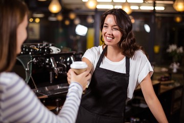 Pretty barista giving disposable cup to woman - obrazy, fototapety, plakaty