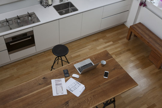 Construction plan, laptop, calculator and cell phone on kitchen table