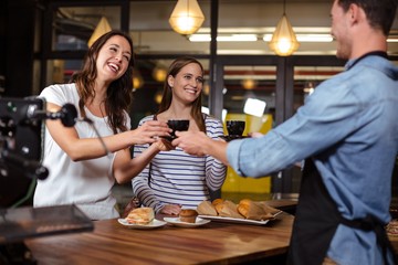 Barista giving coffees to smiling women