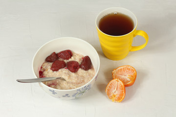 Oatmeal with strawberries, tea and tangerine
