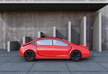 Side view of red autonomous car in front of geometric object background.