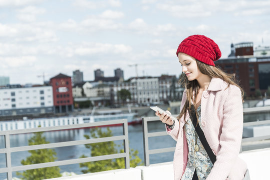 Smiling young woman outdoors looking at cell phone