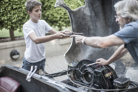 Grandfather and grandson restoring a car together