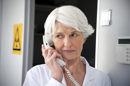 Senior woman working at laboratory making a call