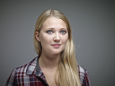 Portrait of young blond woman in front of grey background