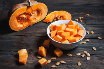 Ripe pumpkin cut slices on a wooden background. 