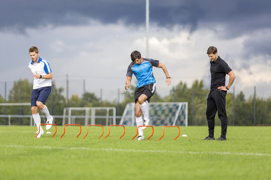 Coach exercising with soccer players on sports field - Powered by Adobe