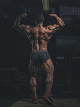 Bodybuilder performing a back double biceps pose in gym