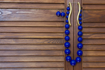 blue beads and earrings  are hanging on wooden background