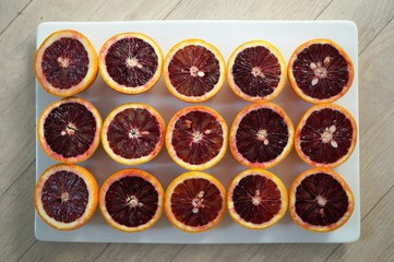 Ruby red blood oranges cut in half on a white platter