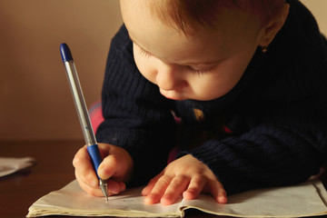 Little beautiful girl writing in her book