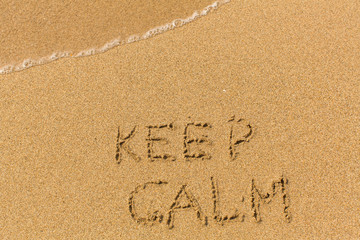 Keep Calm -  drawn on the sand beach with the soft wave.
