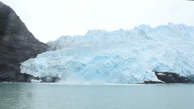 A large chunk of glacier crashing into the water. Handheld shot. 