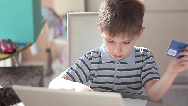 Cute little boy use laptop and credit card