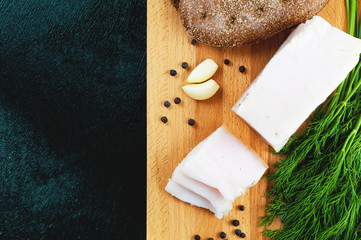 Salty lard with black pepper, garlic and dill on wooden background