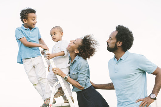 Parents looking at two sons on a ladder