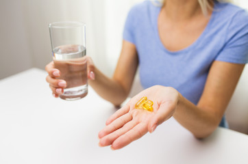 close up of woman hands with capsules and water