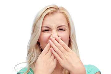 young woman or teenage girl closing her nose