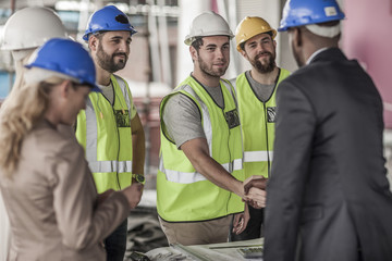 Construction worker and executive shaking hands in construction site