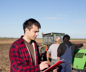 Farmer with workers and tractor on field