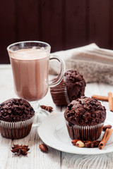
pastries, chocolate muffins with almonds , hazelnuts , cinnamon and cocoa on a wooden background