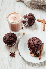 
pastries, chocolate muffins with almonds , hazelnuts , cinnamon and cocoa on a wooden background