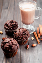 
pastries, chocolate muffins with almonds , hazelnuts , cinnamon and cocoa on a wooden background