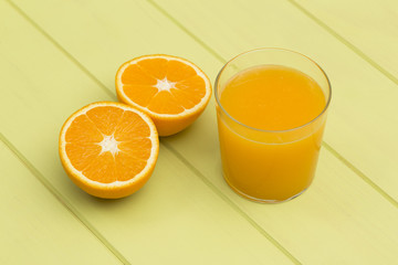 Orange juice and slices of orange on green table