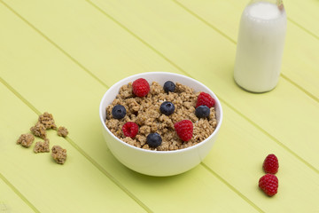Granola in a bowl with milk, raspberries and blueberries