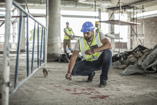 Construction worker spaying marks on floor in construction site