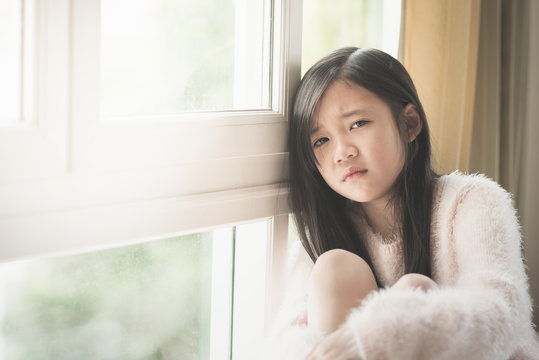 Portrait of asian beautiful sad girl at the window
