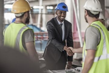 Construction worker and executive shaking hands in construction site