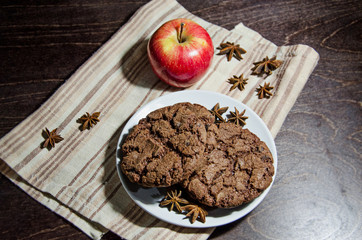 A plate with chocolate cookies and  an apple