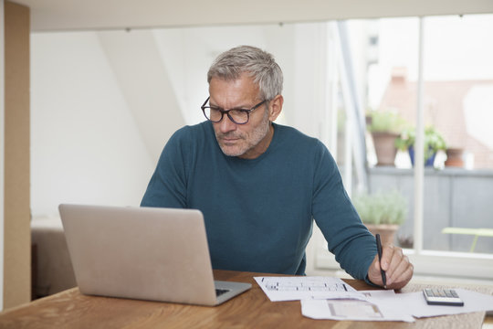Mature man at home using laptop