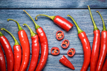 Red hot peppers on blue wooden table background.