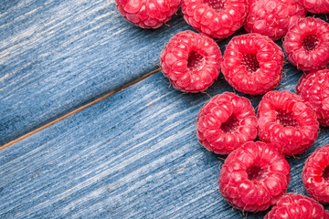 Fresh raspberries on blue wooden table.