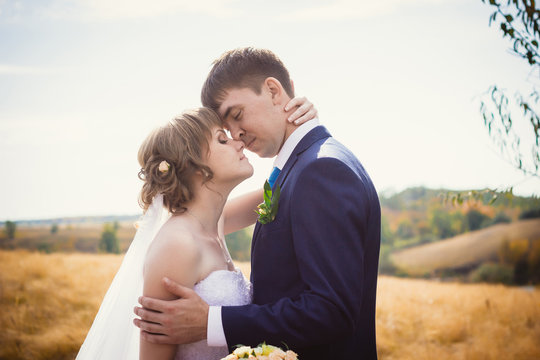 young bride and groom on the background of field