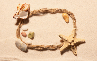 Fototapeta na wymiar Frame of rope with starfish, seashell and stones on sand