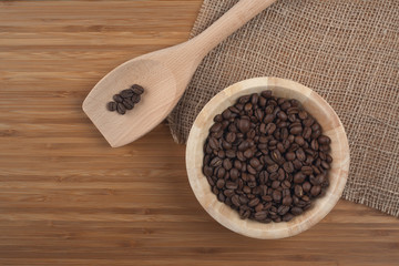 Coffee beans in bowl on wooden background
