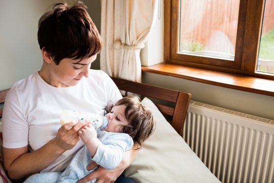 Cute mother bottle feeding her baby
