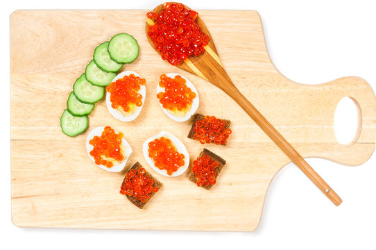 Canapes with red caviar on wooden board