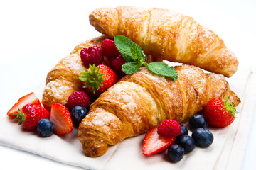 Fresh tasty croissants with berries on white background