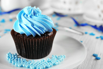 Delicious chocolate cupcake with blue cream on decorated wooden  table, close up