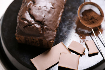 Chocolate cake with icing and cocoa powder on baking dish over white table